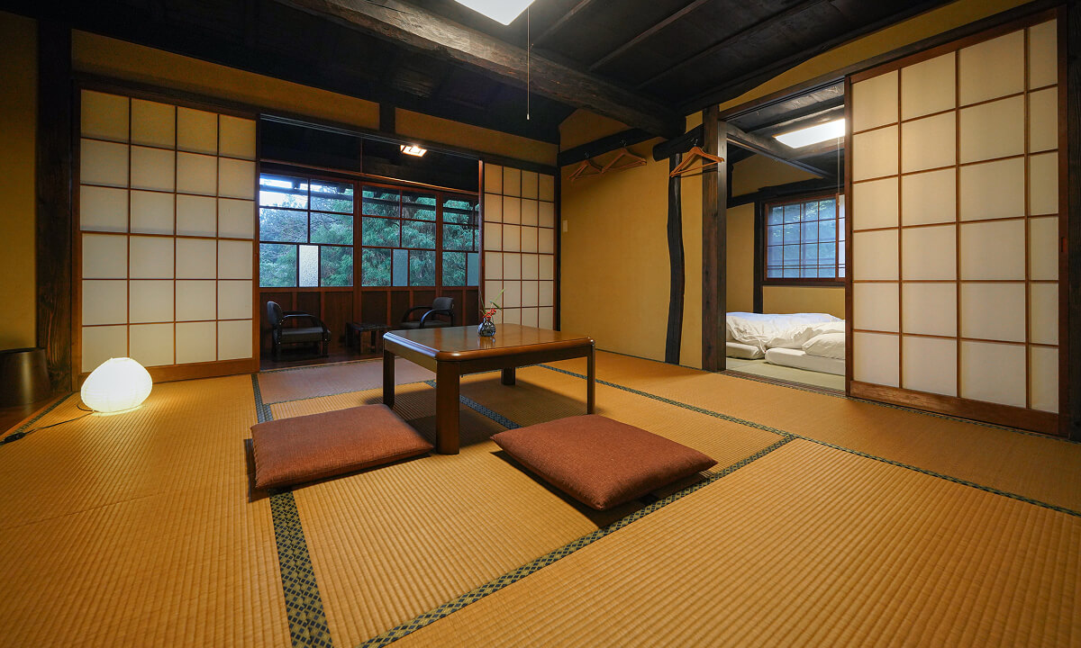 雪灯のインテリア、畳に座卓が置かれたお部屋、奥にもう一部屋布団の敷かれたお部屋が見える